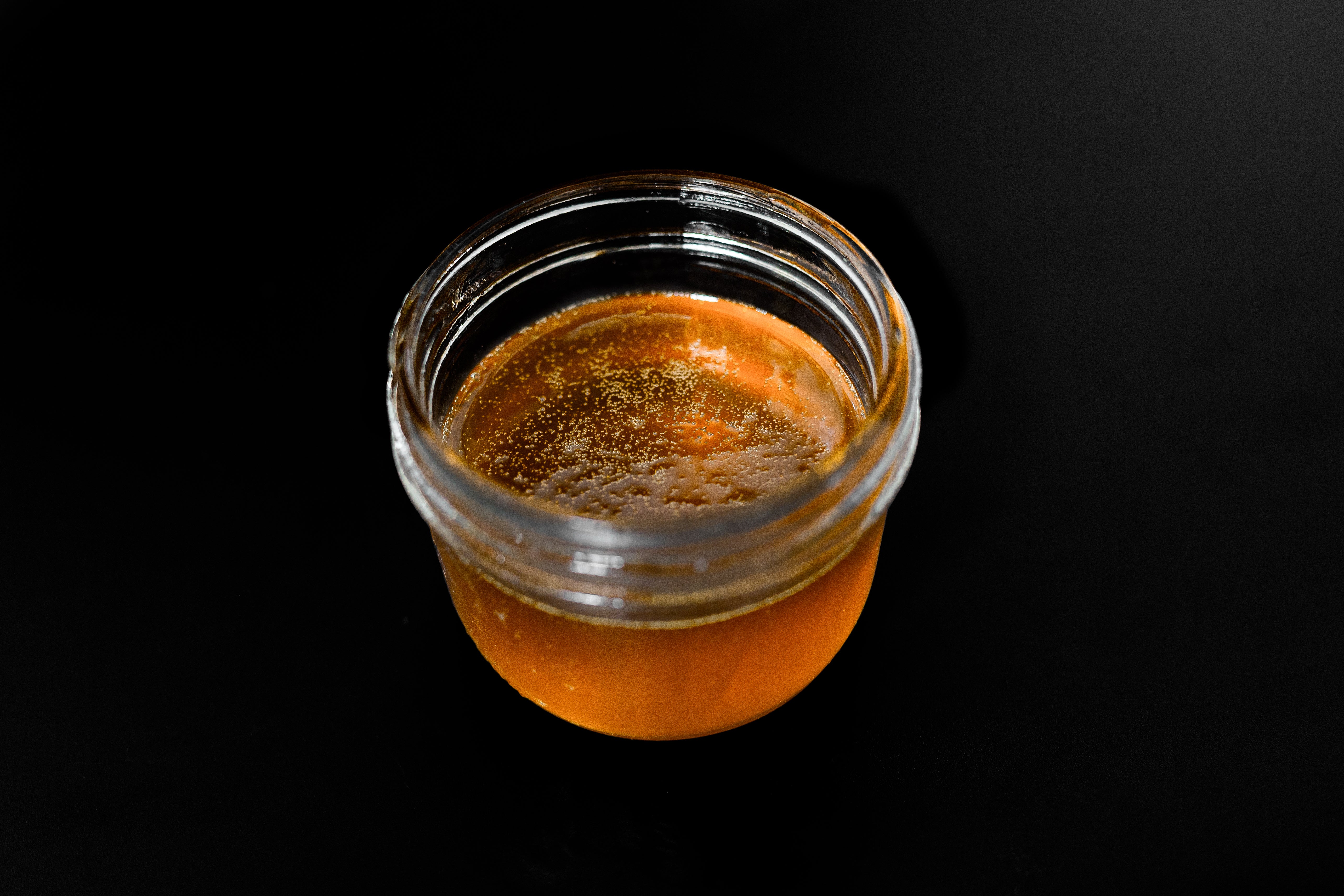 A glass jar is filled with amber-colored cannabis concentrate oil that's rich in flavor and potency.