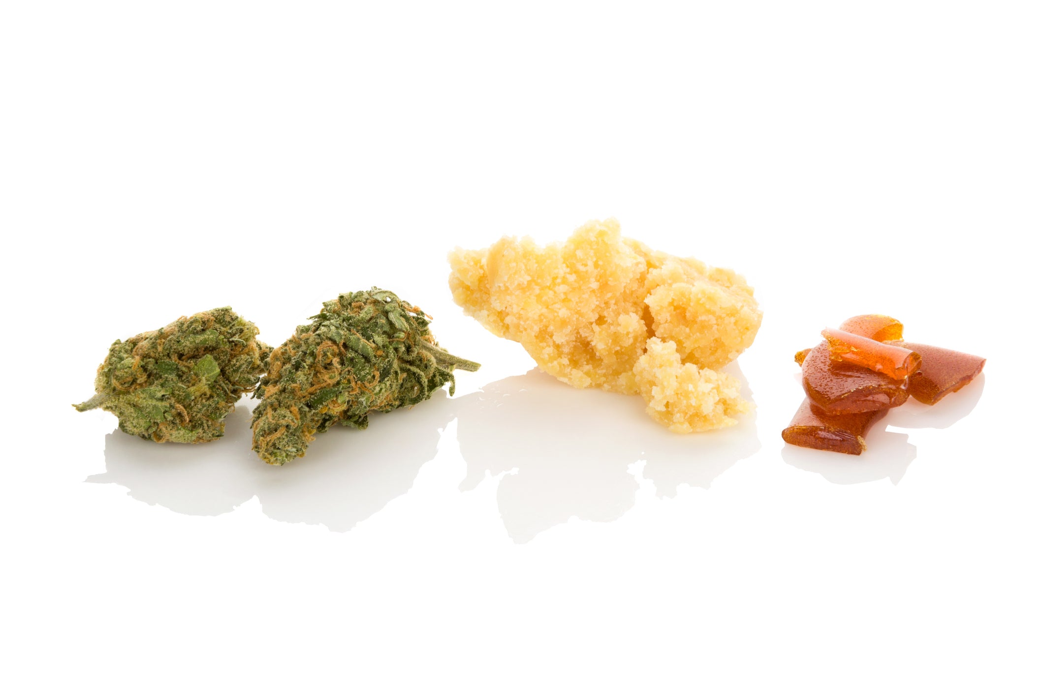 Cannabis flower nugs sit next to crumble and shatter concentrates for dabbing.