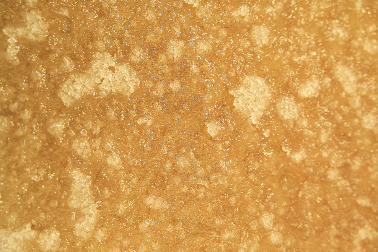 A live resin cannabis extract with an amber color has a crumble-like texture.