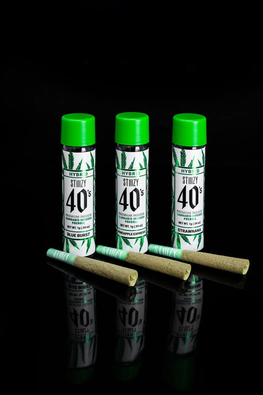 Infused cannabis pre-rolls of a hybrid strain lie in front of their jars with green caps.