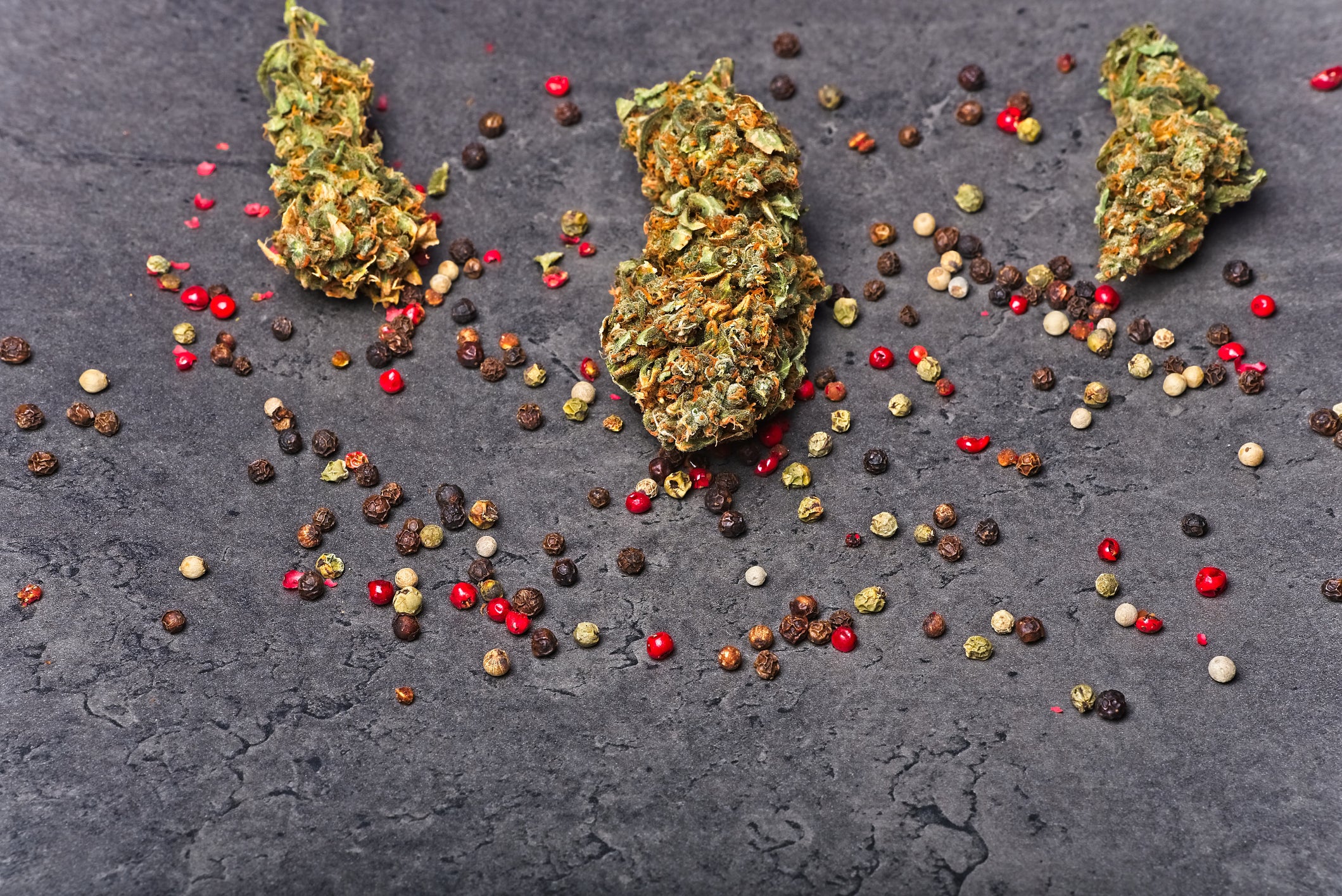 Peppercorns with the beta-caryophyllene terpene are next to cannabis flower buds with a similar flavor.