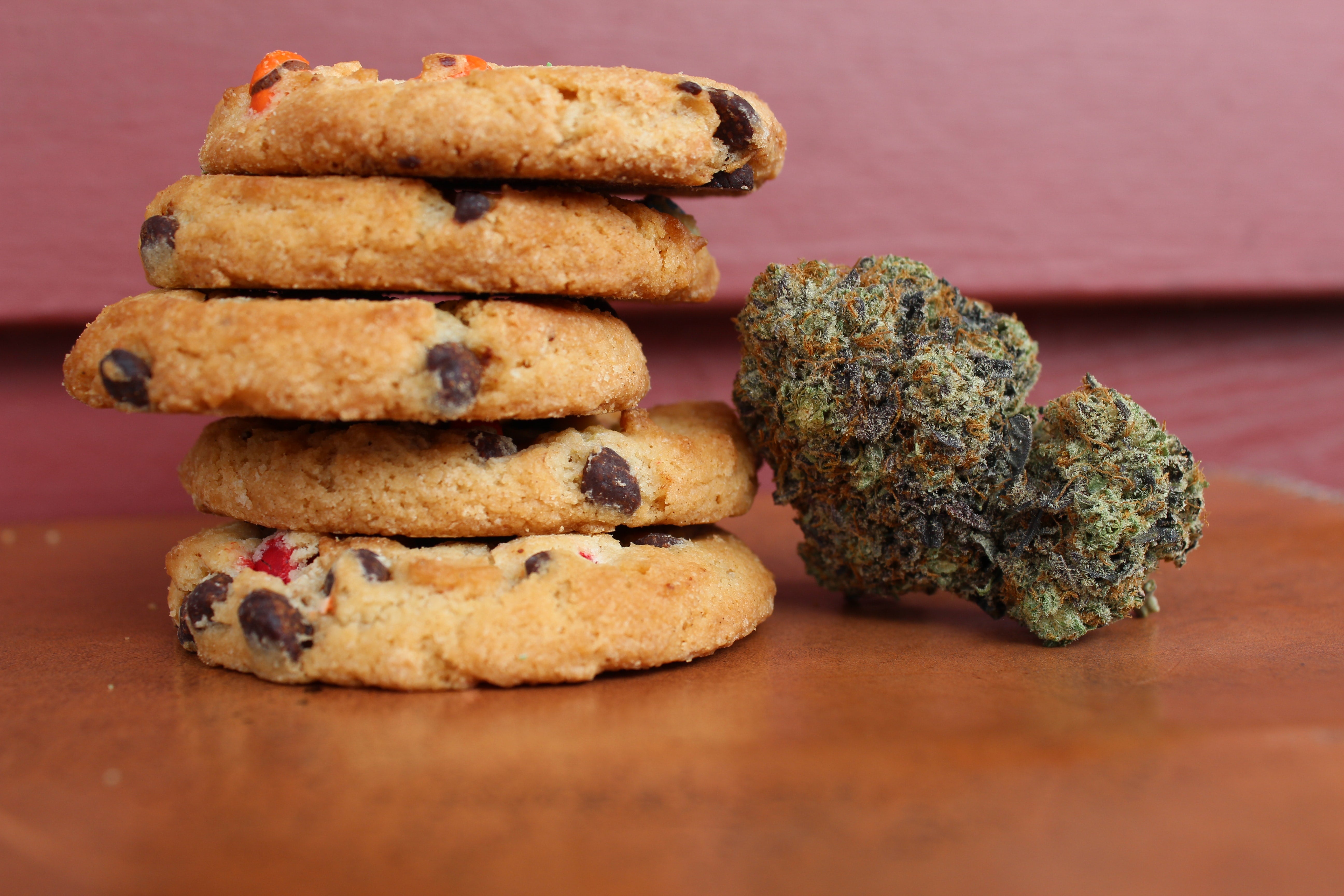 A stack of cannabis cookies stand next to a nug of cannabis flower.