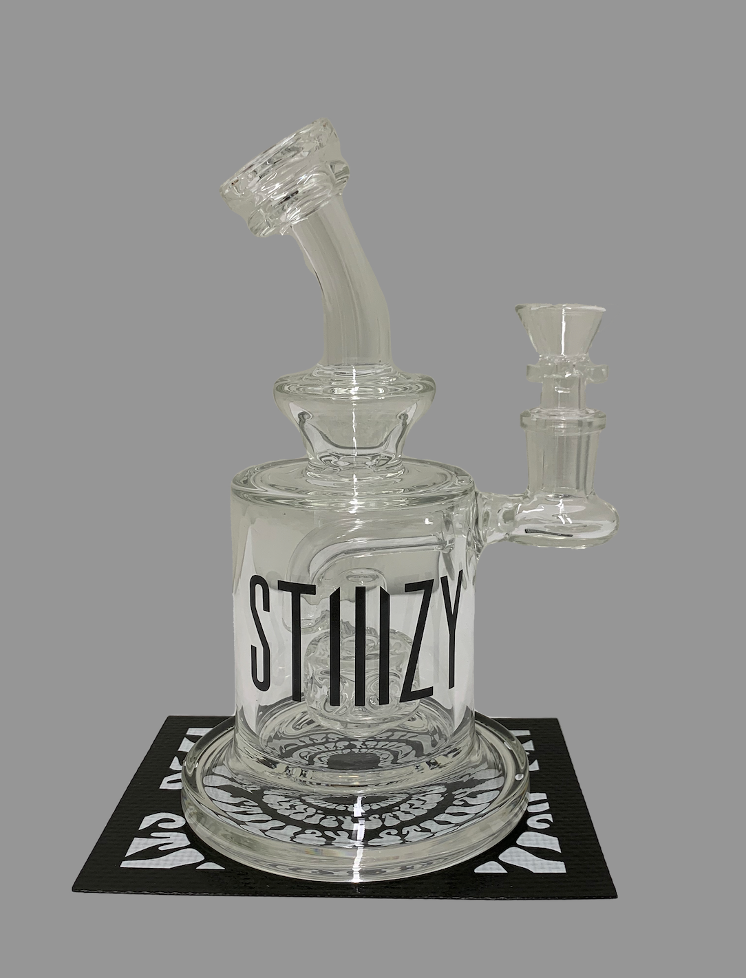 A large glass dab rig from STIIIZY sits on a black and white mat.