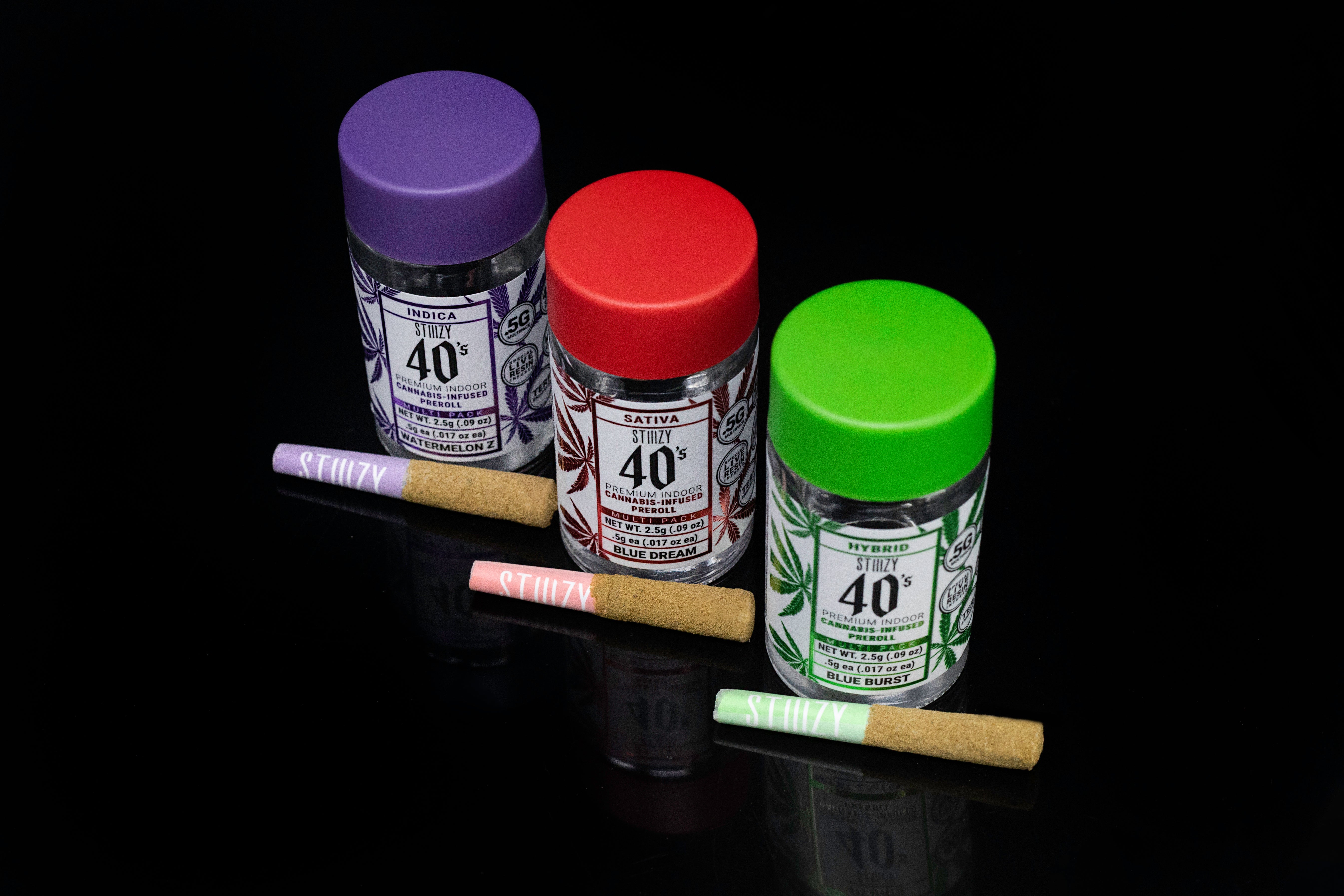 Three infused pre-rolls made from either hybrid, indica, or sativa cannabis flower, lie in front of their jars.