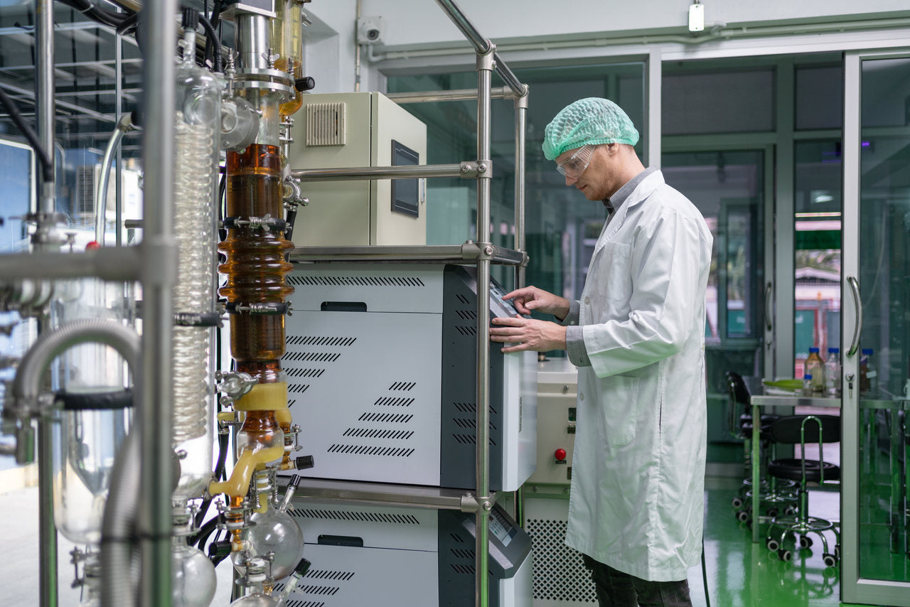 A lab technician operates machinery to make cannabis extracts using solvents.