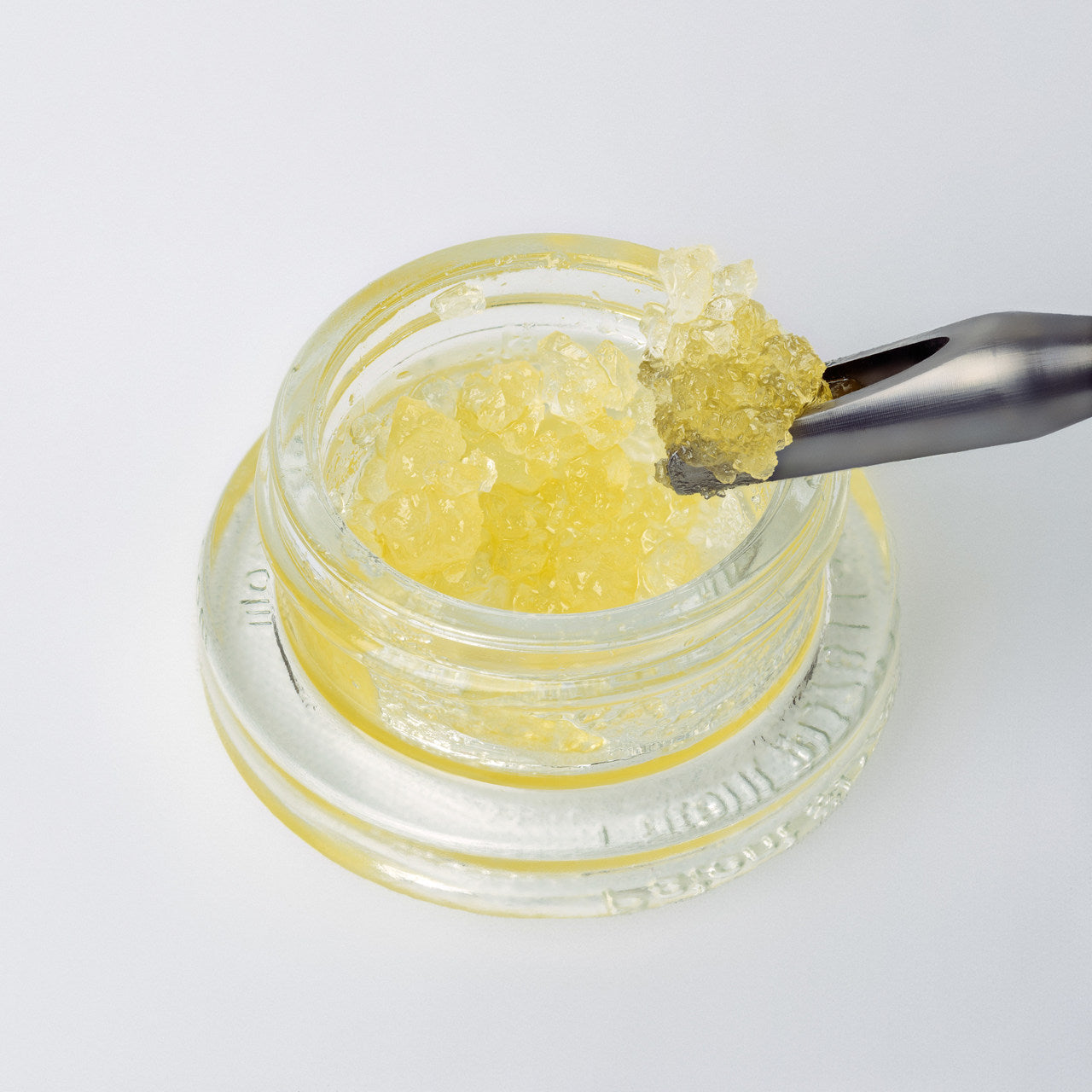 Live resin diamonds, a cannabis extract, are scooped out of their glass jar with a metal dabbing tool.