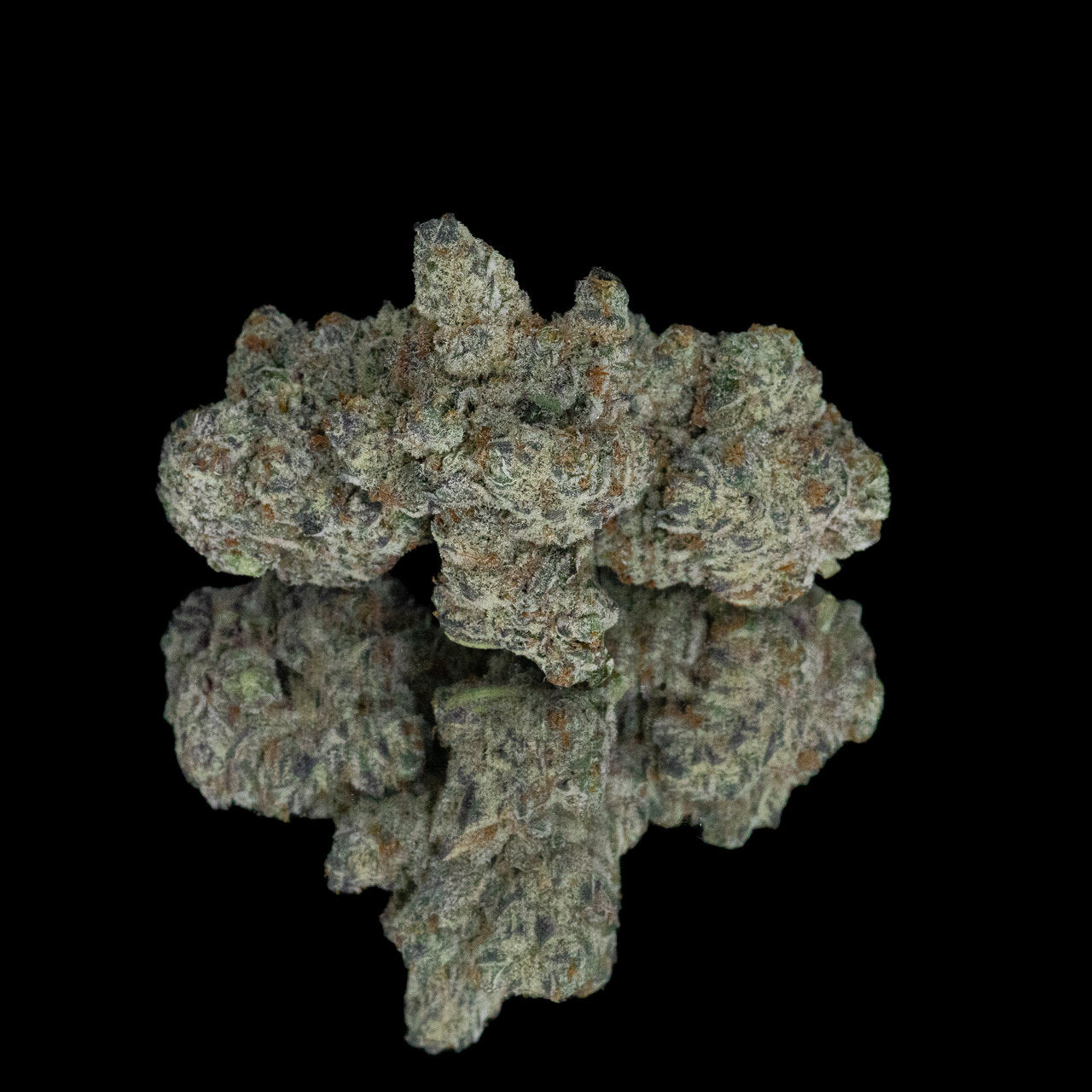 Three nugs of cannabis flower from the London Pound Cake strain rest against their reflection on a black surface.