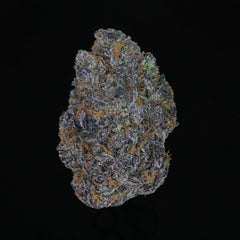 A beautiful, colorful nug of cannabis flower from the Rainbow Kush strain sits in front of a black background.