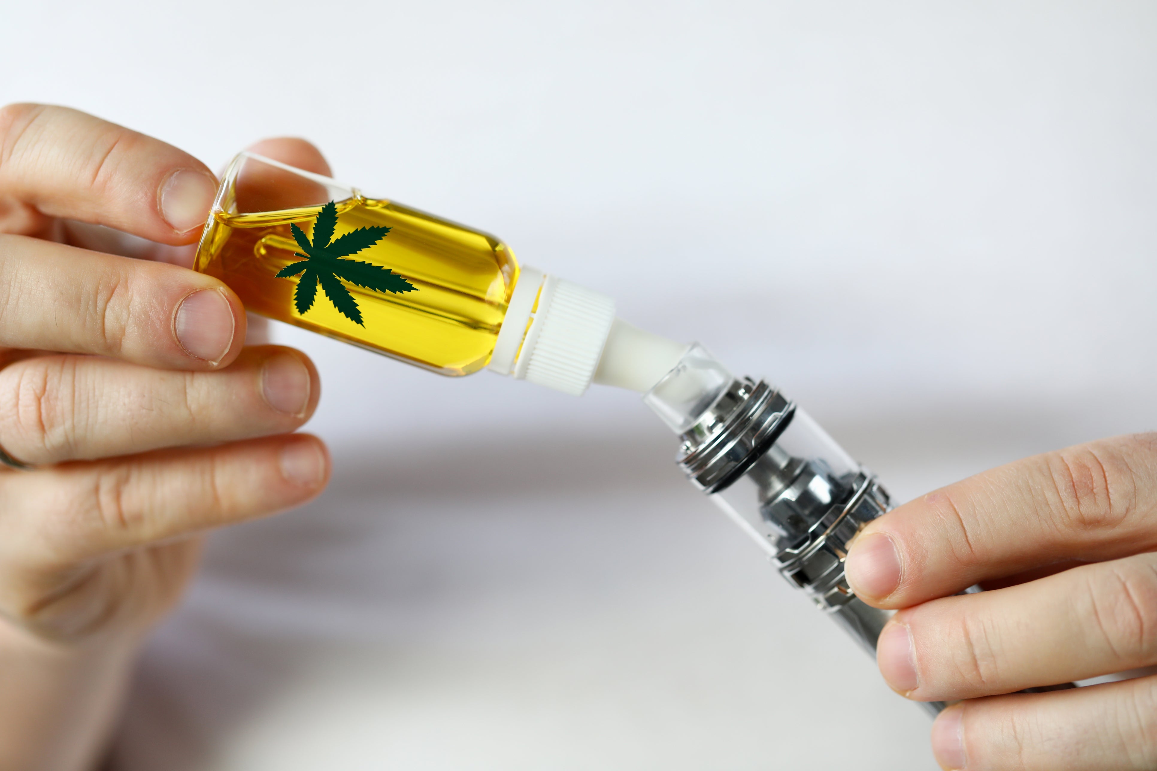 A weed vape cartridge is being filled up with THC oil and cannabis-derived terpenes from a tincture.