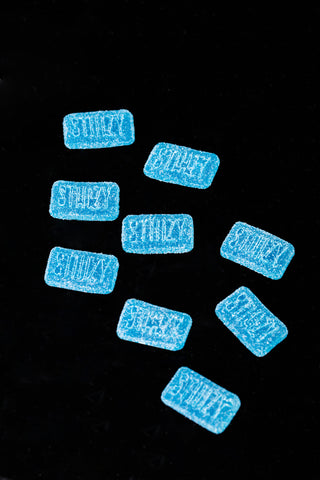 Bright blueberry-flavored weed gummies from STIIIZY laid out against a black backdrop.