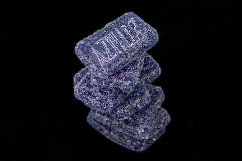 A pile of purple weed gummies with grape flavor made from a specific strain of weed.