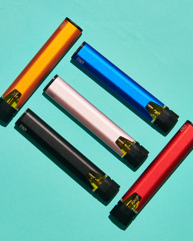 A colorful colleciton of STIIIZY's weed pens laid out on a turquoise background.