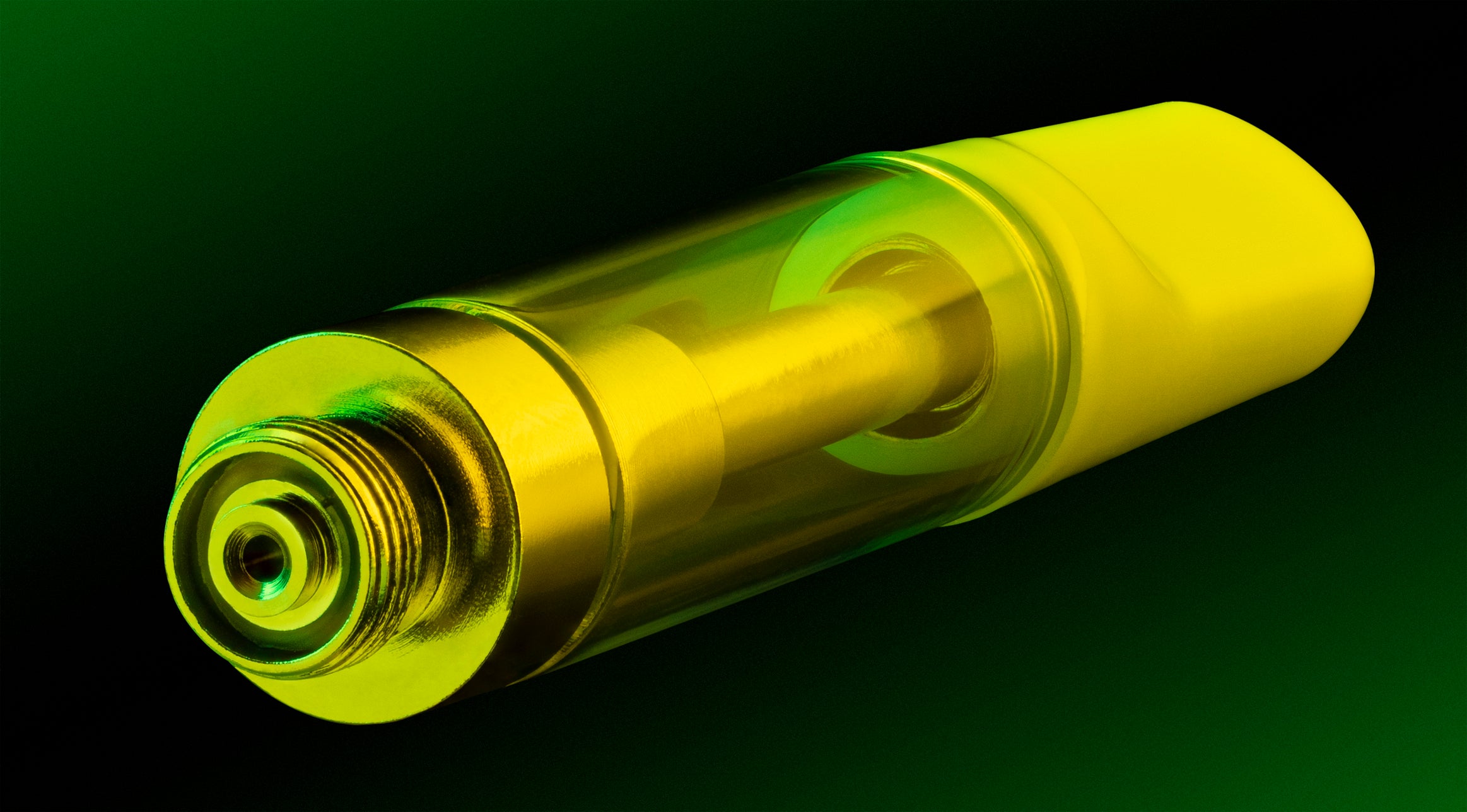 An empty weed vape cartridge in a neon green light lies against a black background.