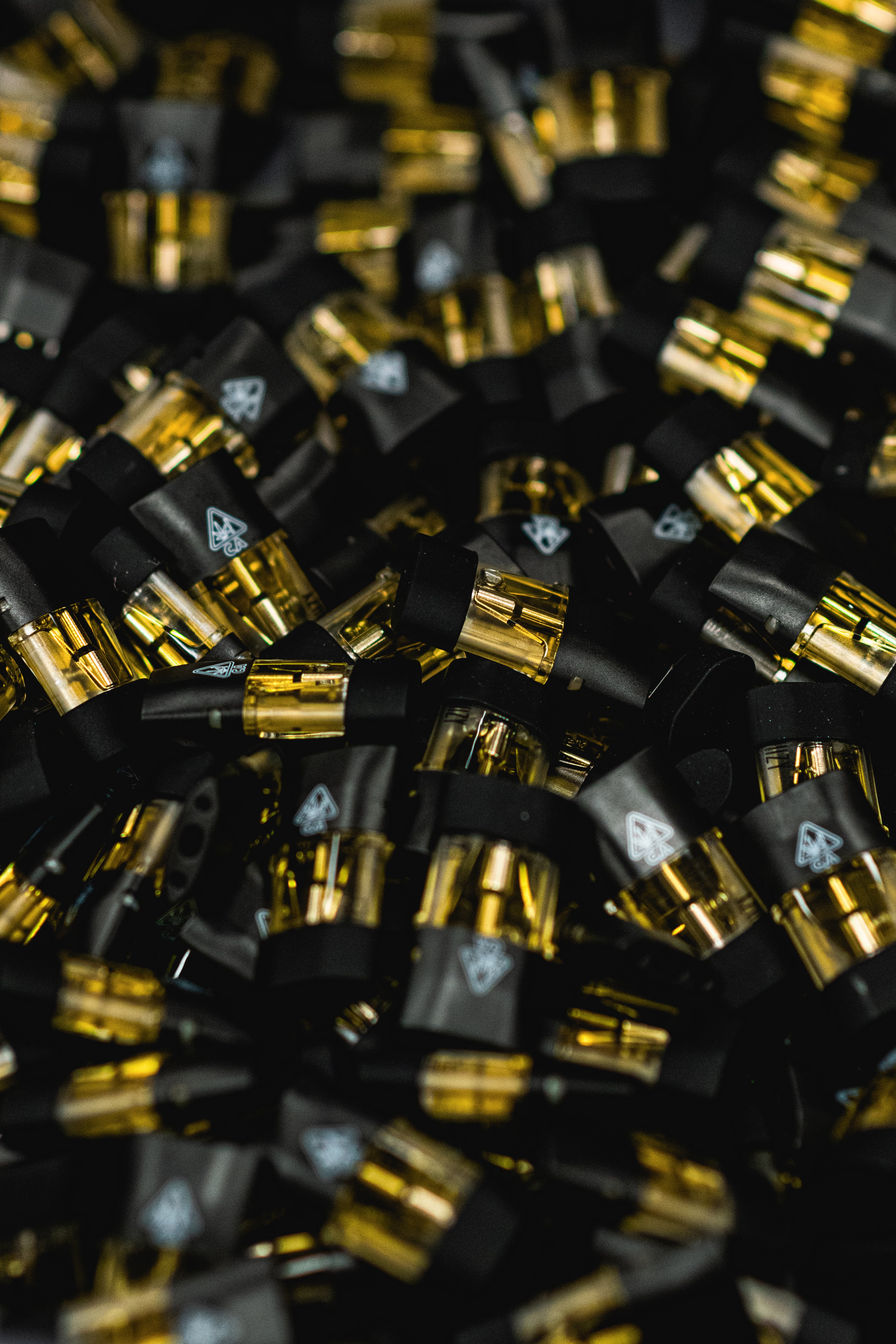A large pool of black-capped weed vape pods with distillate are being showcased.