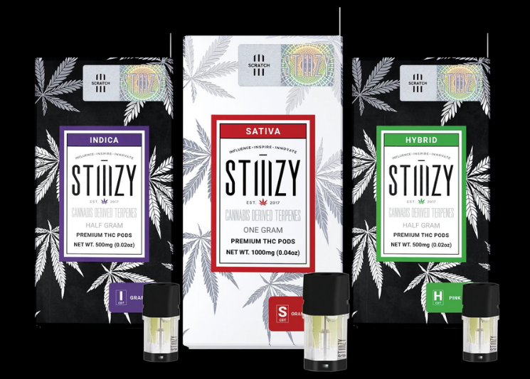 Three weed vape pods with cannabis-derived terpenes stand next to their black and white packages.