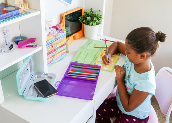 A child does homework at a desk by a PhoneSoap 3