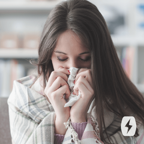 A woman blows her nose with a tissue