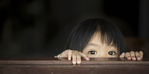 child looking through blind