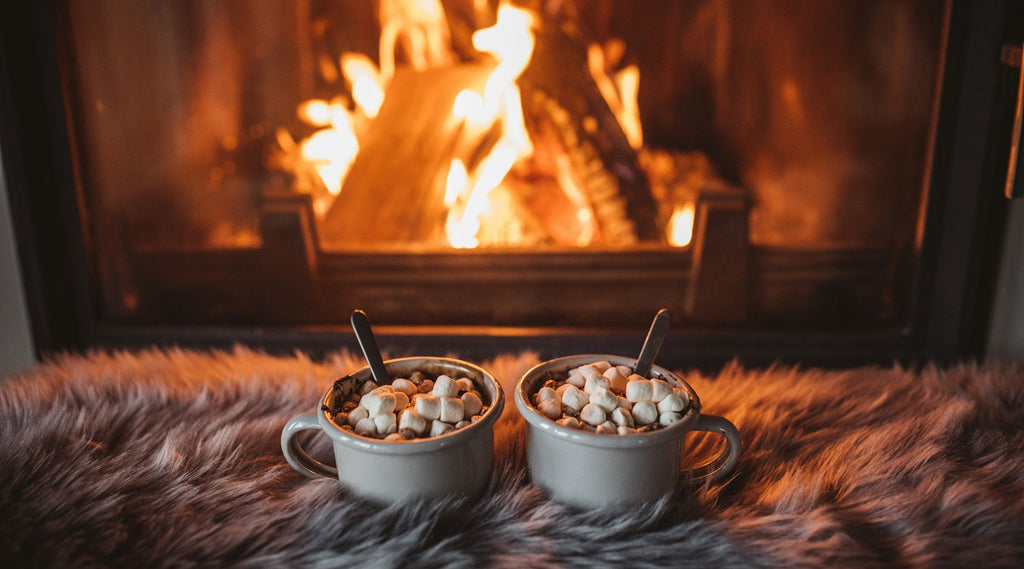 Two cups of hot chocolate on cozy fur in front of fireplace