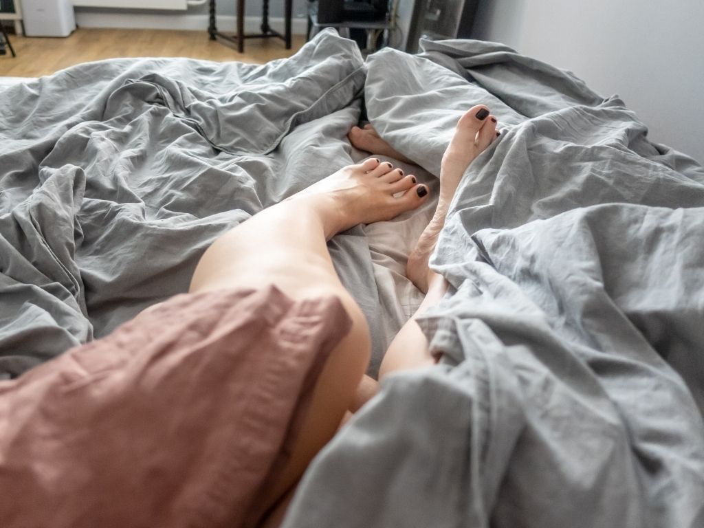 Man and woman's legs tangled up in bed sheets