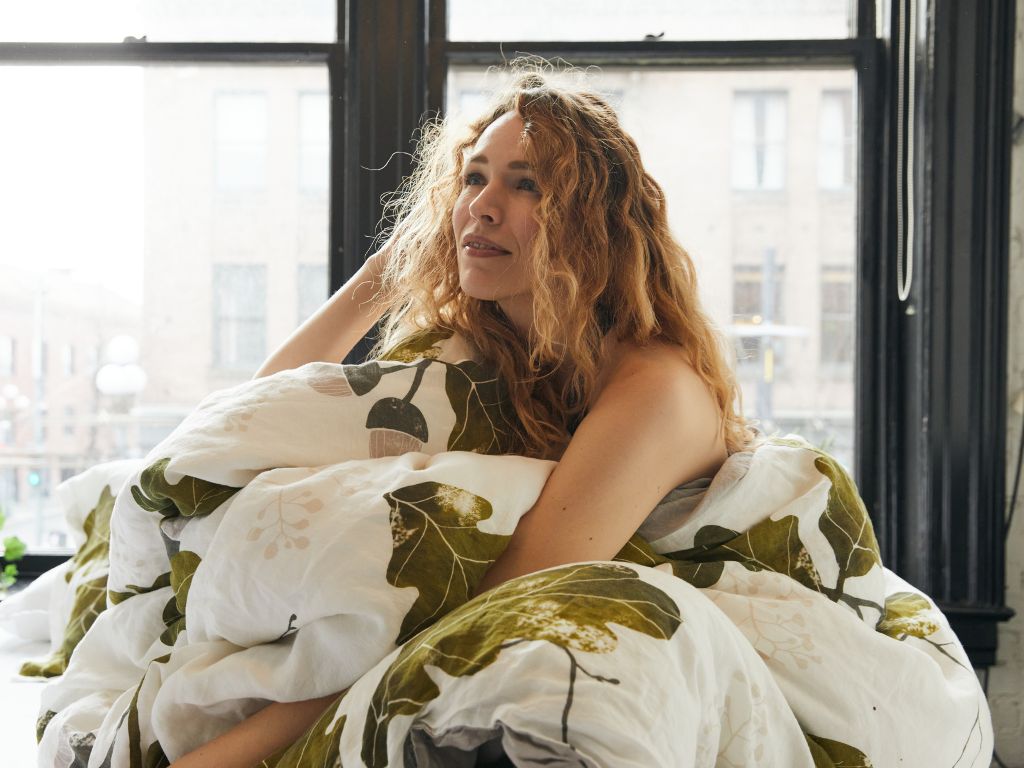 Woman with organic European flax linen duvet cover with acorn and oak leaves design by The Modern Dane