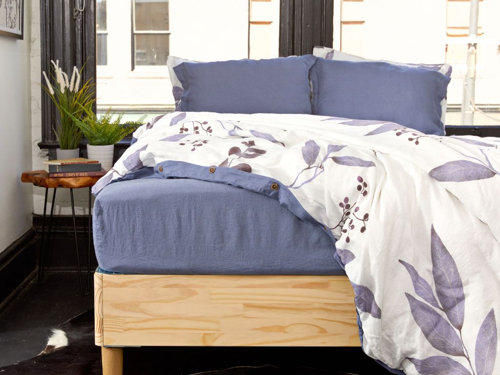 Organic European flax linen duvet cover draped over a bed with a matching blue linen fitted sheet and pillowcases