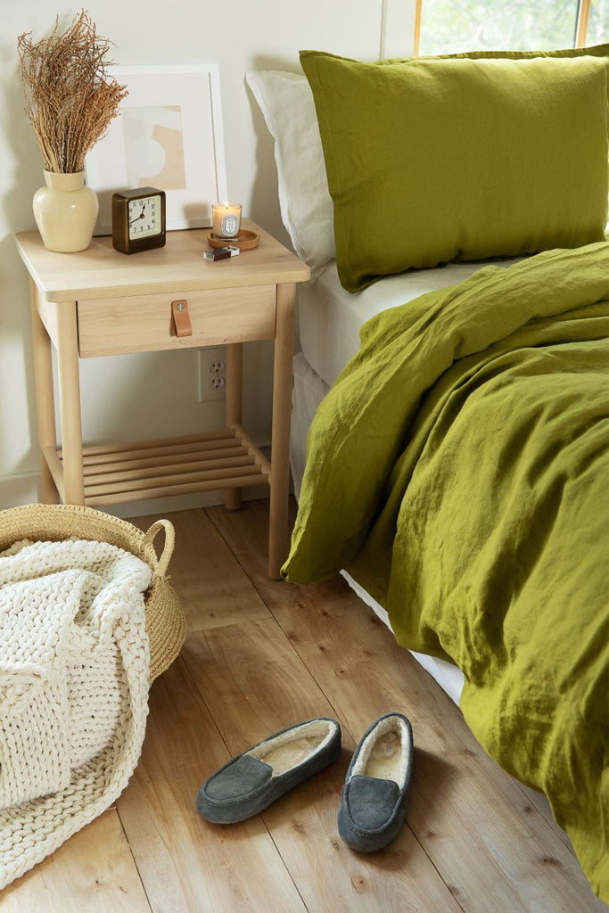 Chartreuse green organic flax linen duvet cover set on a bed with comfy slippers next to it