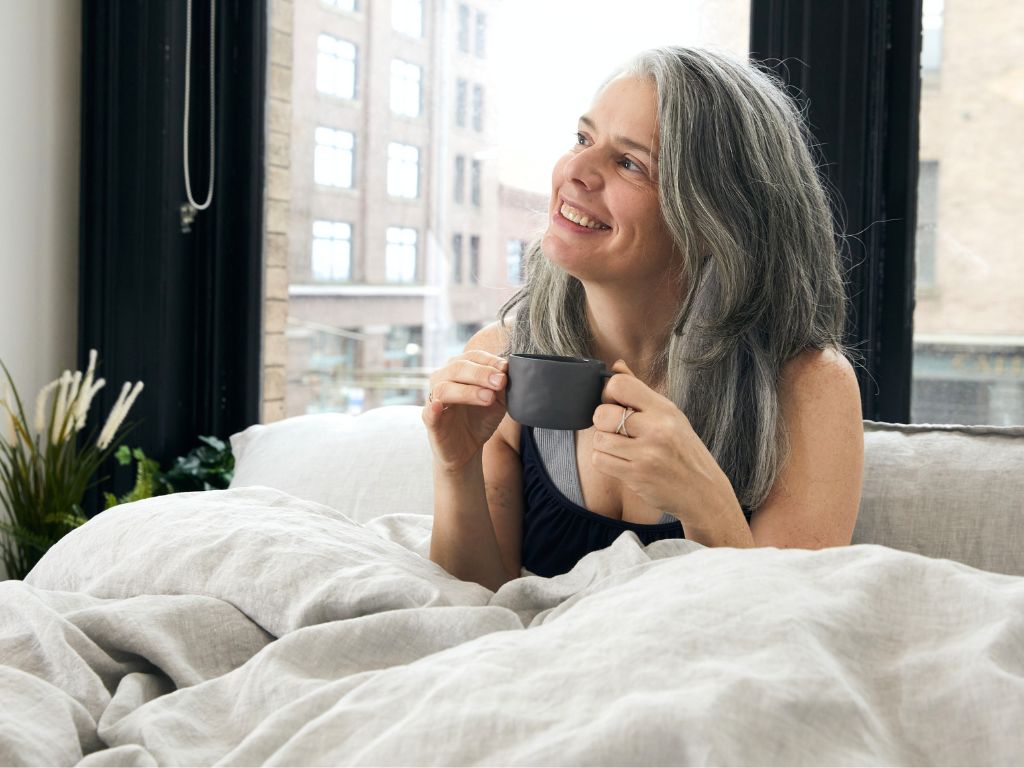 Woman drinking tea in chambray grey organic European flax linen duvet cover set by The Modern Dane