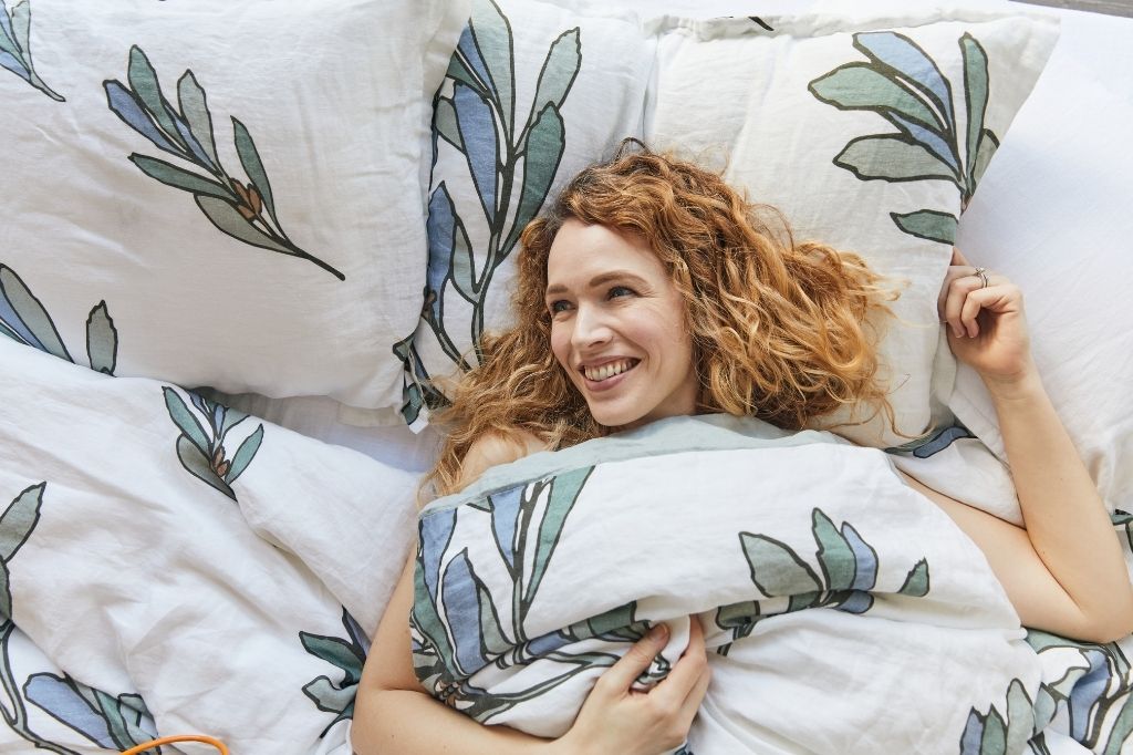 Woman in bed made with organic European linen bedding with modern Scandinavian design from The Modern Dane