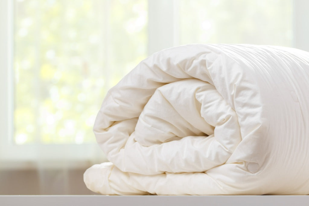 Rolled up duvet is lying on the dresser against the background of a blurred window