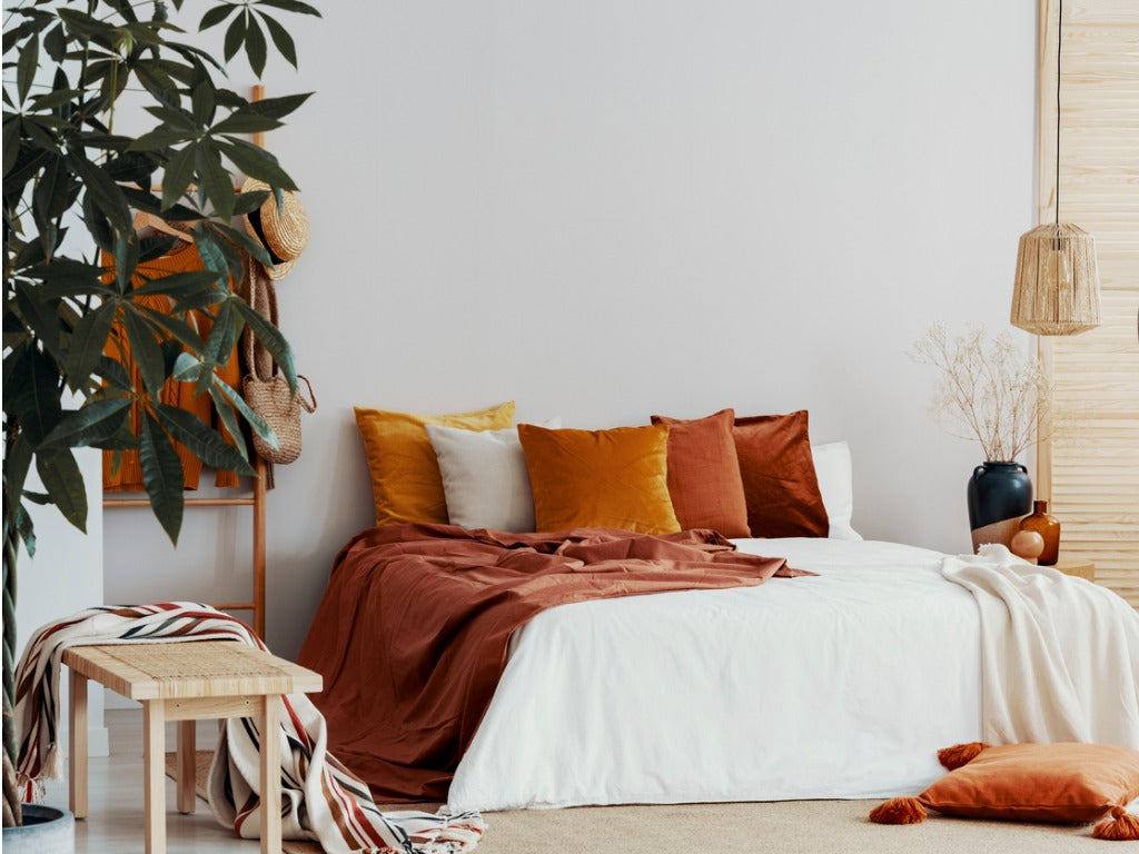 Autumn colored pillows on king size bed in chic bedroom interior 