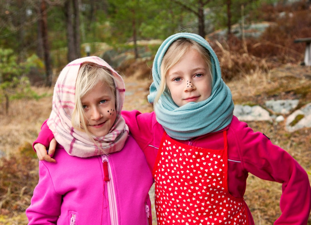 Two blond sisters dressed up as a witch smiling at camera.. In Sweden children dress up as wishes during Easter and go around giving out handmade Easter cards expecting to get some candy in return