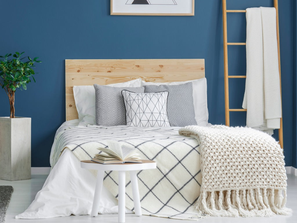 Cozy bedroom interior with a double bed, wooden cabinet, chandelier and blue wall