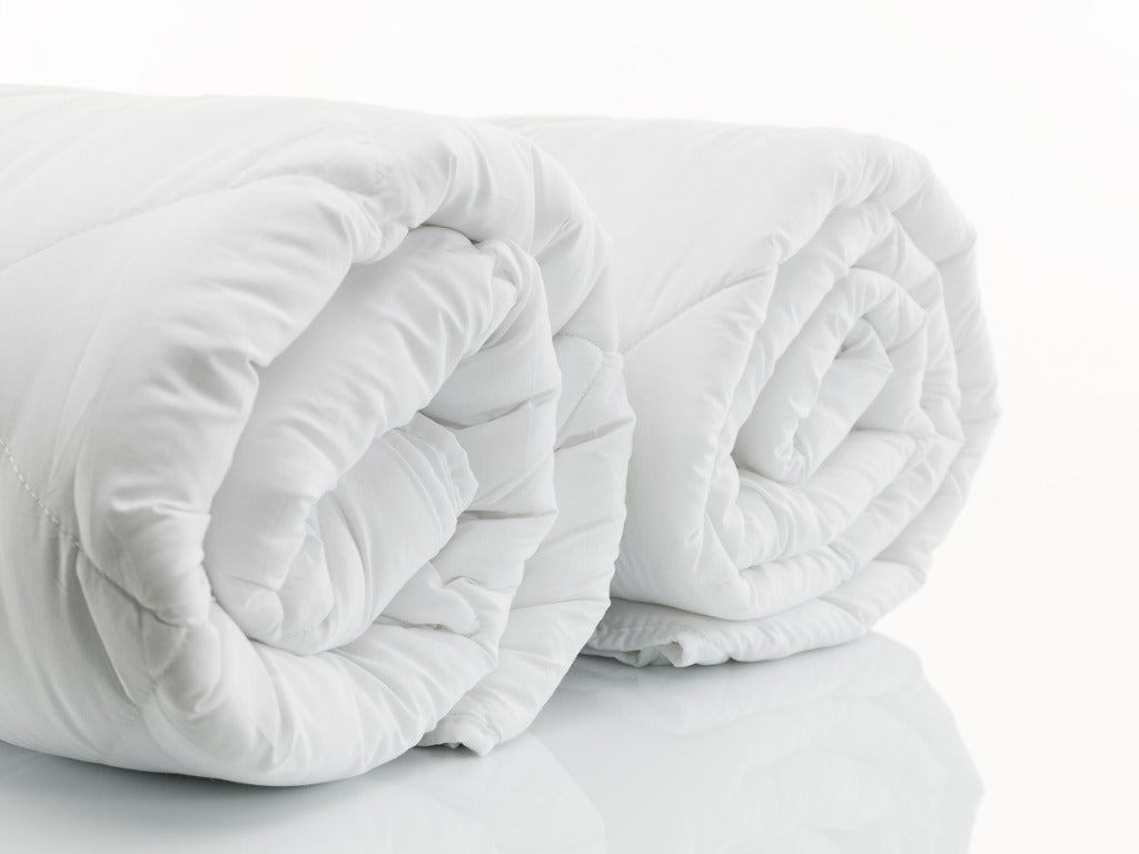 Two rolled up duvets on a white background 