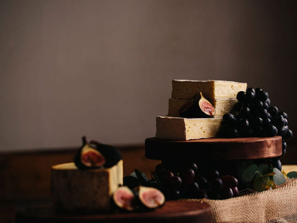 Cheese board grazing table with fruit and dark wooden cheese board