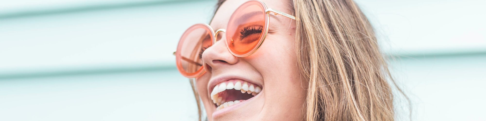 Ung kvinder med solbriller griner med tænder
