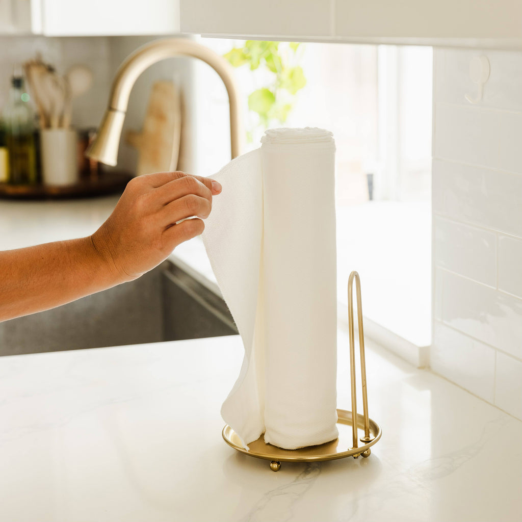 A hand pulling a single Esembly Paperless towel off of a roll in a kitchen
