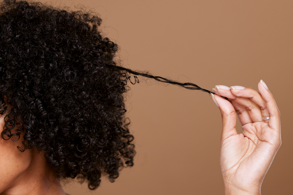 Woman stretching her curly coily hair strand