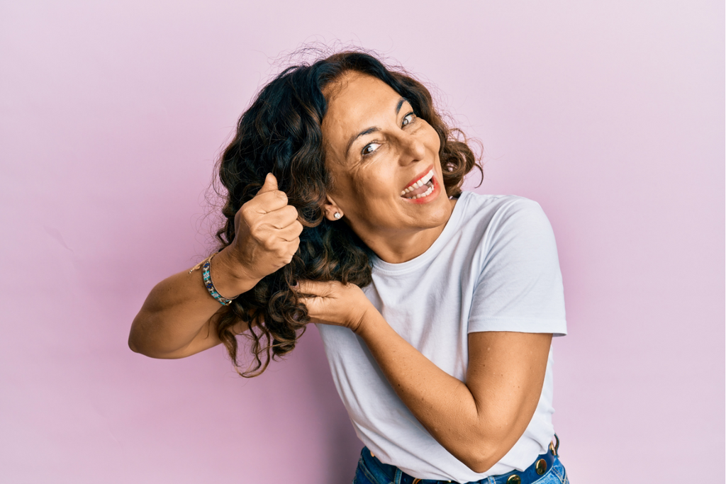 Woman curling hair using cosmetics products, doing curly style treatment on hair