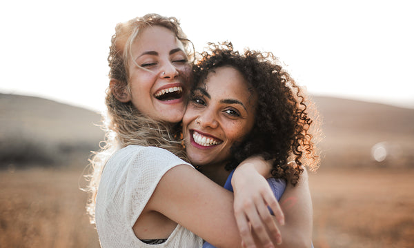 women with natural hair hugging and laughing