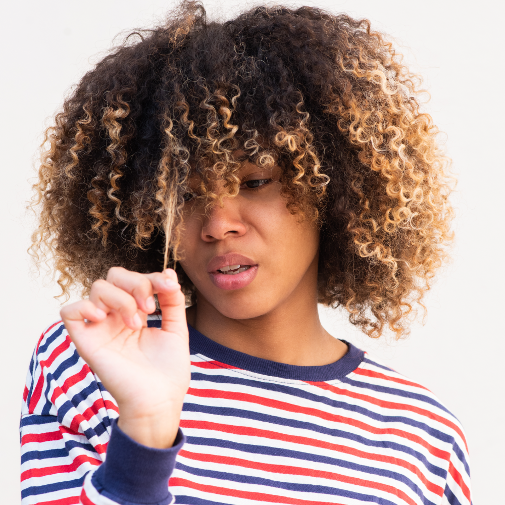 woman looking at strands of her natural hair