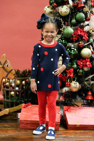 girl in front of a Christmas tree in a polka dot sweater