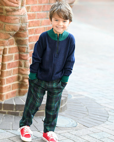 A young boy in a green tartan pant and navy and green sweater