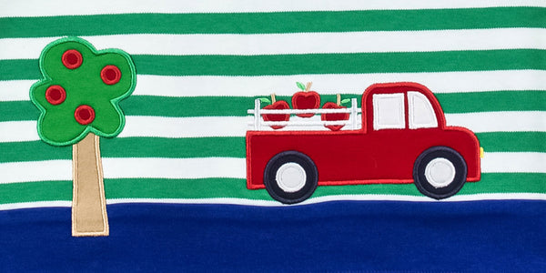 Close up of a sweater featuring a red truck and apple tree