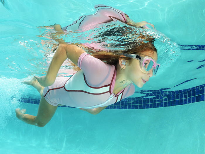 Kid swimming with earplugs on