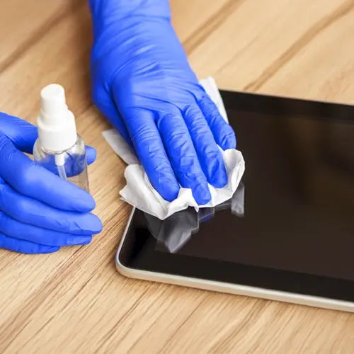 Person sanitizing a tablet screen with a cleaning wipe
