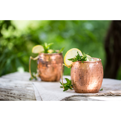 2 small cups of moscow mules with a slice of lemon in each cup.