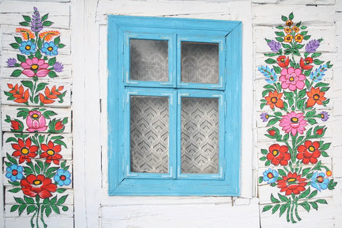 blue cottage window with white walls painted in floral motives