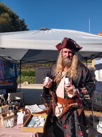 Pirate holding Vianek skincare bottles at the booth of Alina Cosmetics, Thousand Oaks Rotary Street Fair