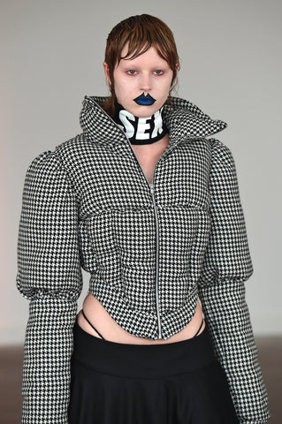 LULA LAORA AW21 Getty Images, womenswear model has blue lips and short hair. She wears a houndstooth puffer jacket and black trousers. 